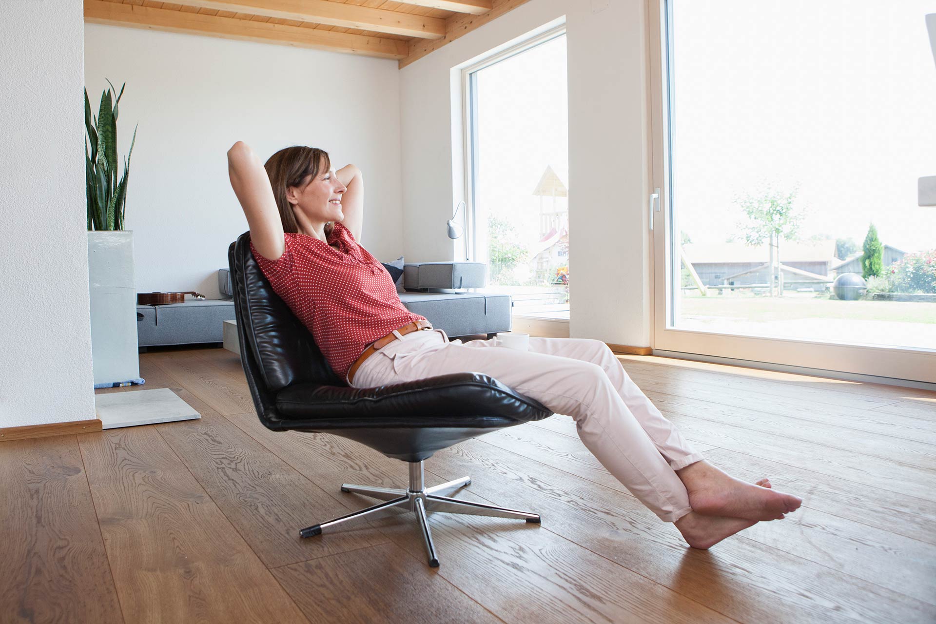 Glückliche Frau Sitz in Sessel in Ihrem Wohnzimmmer